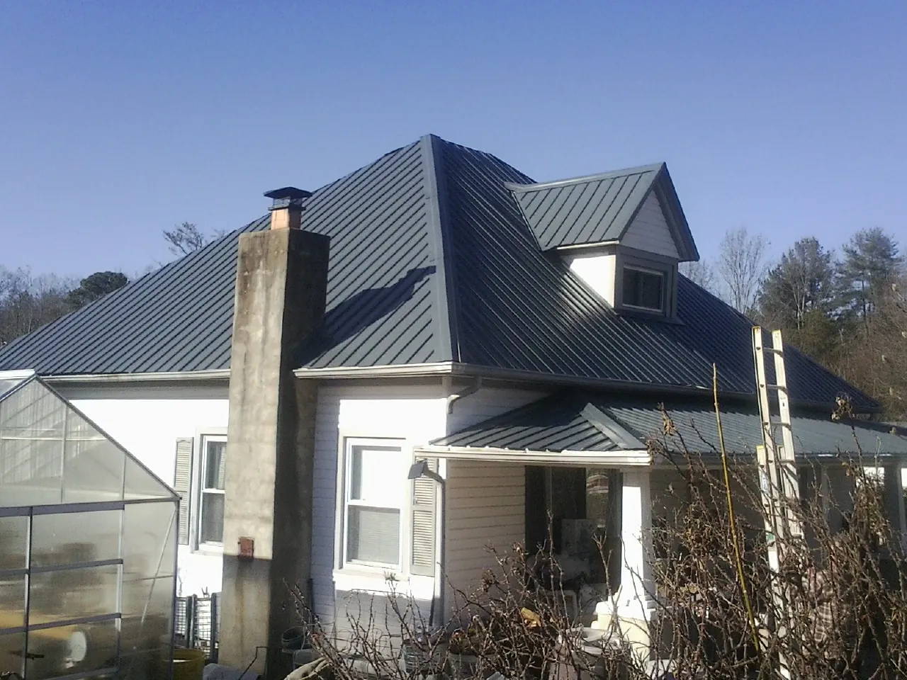 Dark blue standing seam metal roof on a white farmhouse with dormer — Slate & Tile Roof Repair by Roofing Brothers in Chattanooga