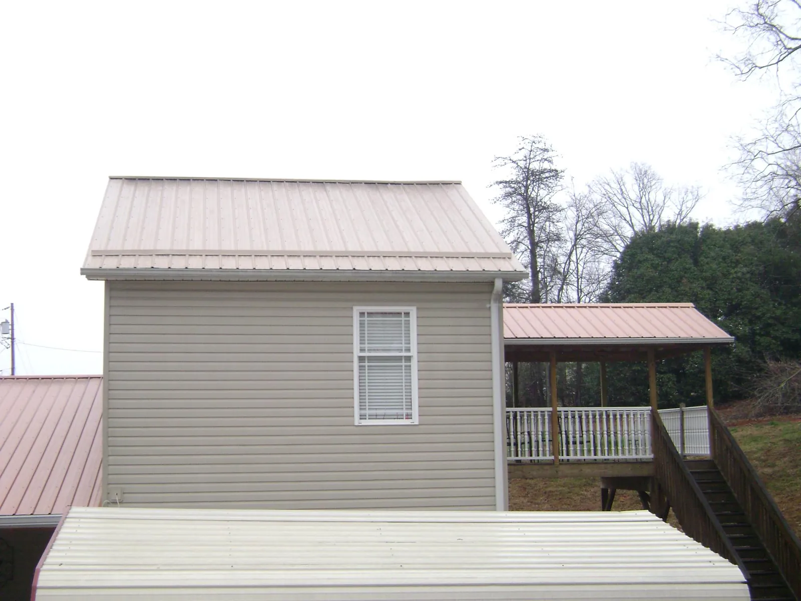 Tan metal roofs on a two story addition and attached porch, from a Roof Replacement job in Chattanooga