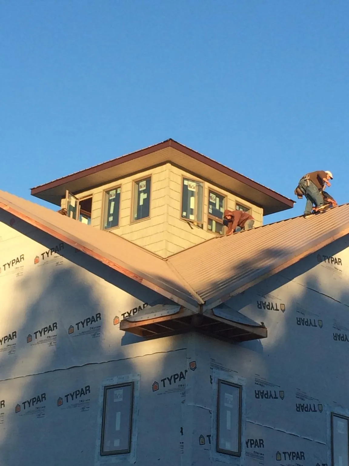 Roofers working around a rooftop cupola on a new metal roof at sunset — Roof Waterproofing in Chattanooga by Roofing Brothers